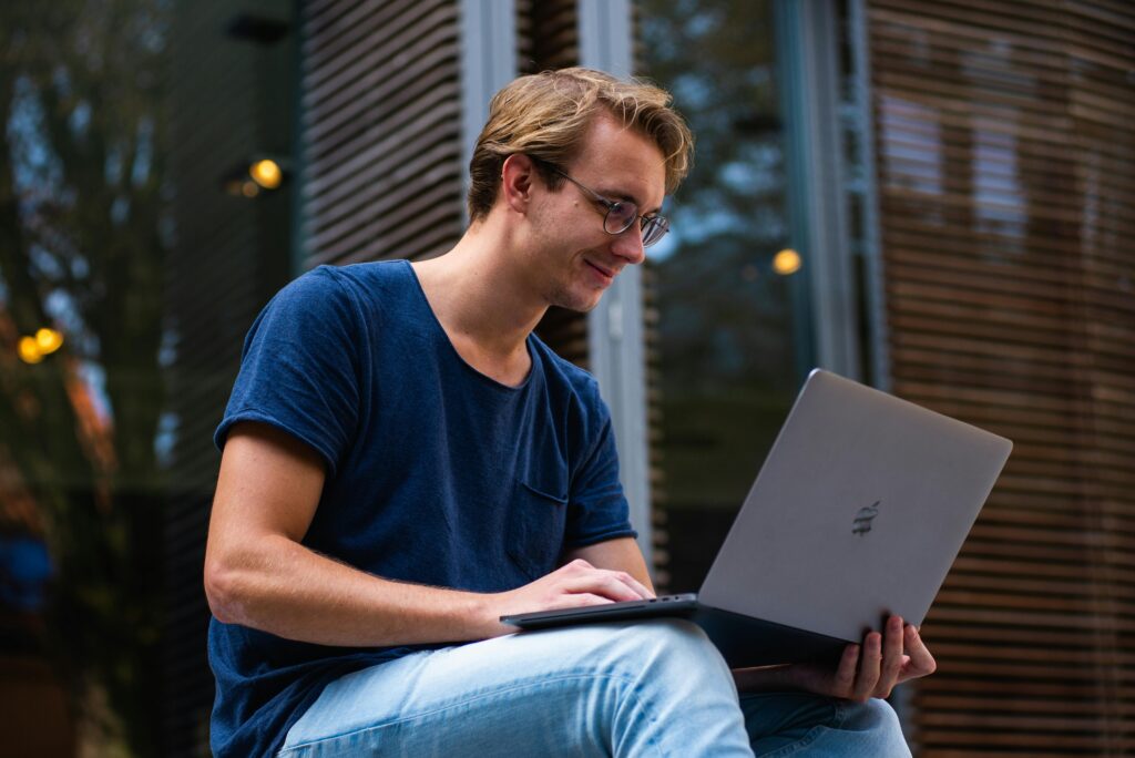 A young man sitting outdoors in Leiden, Netherlands, working on a laptop.